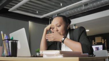 Genç Afrikalı Amerikalı kadın ofisteki masaüstünde uyuyor.