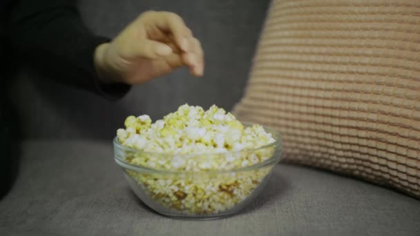 Mano femminile raccogliendo popcorn dal primo piano secchio di carta. Primo piano di una donna che mangia pop corn al cinema. Concetto di cibo cinematografico. Mano femminile che prende popcorn . — Video Stock