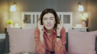 Kanepede oturan, televizyon izleyen ve el ele tutuşan genç yünlü kadın.