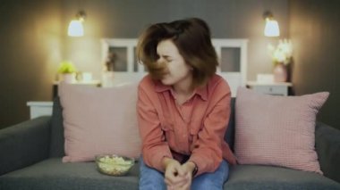 Kanepede oturup televizyon izleyen hayal kırıklığına uğramış bir kadın.