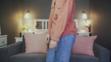 Genç bir kadın kanepede oturur ve televizyon izler. Kameraya bak.