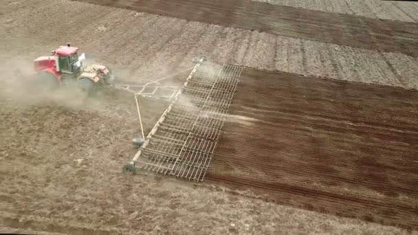 Vista aérea de um poderoso trator saturado de energia com uma grande força de gancho, realizando lavoura para semear culturas de inverno com um cultivador de discos no outono — Vídeo de Stock