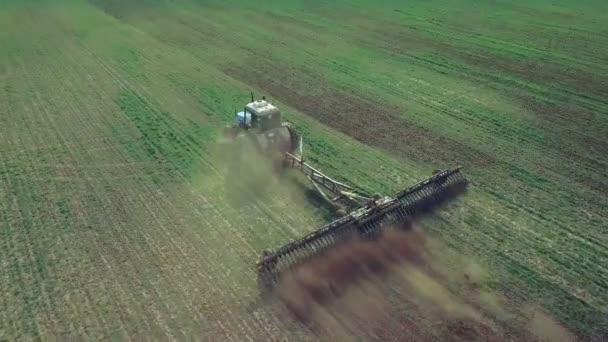 Fermier dans un tracteur avec un semoir prépare la terre pour semer des cultures céréalières dans le champ labouré. Planter des graines dans la poussière. Travaux agricoles de printemps. Vue aérienne du dessus, drone voler vers l'avant suivre tracteur 