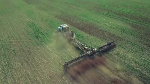 Fermier dans un tracteur avec un semoir prépare la terre pour semer des cultures céréalières dans le champ labouré. Planter des graines dans la poussière. Travaux agricoles de printemps. Vue aérienne du dessus, drone voler vers l'avant suivre tracteur 