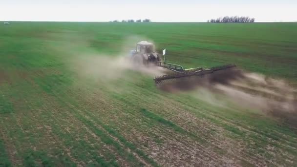 Büyük bir kanca kuvvetiyle enerji dolu güçlü bir traktörün hava görüntüsü, sonbaharda kış ekinleri için bir disk ekiciyle ekin ekiyor. — Stok video