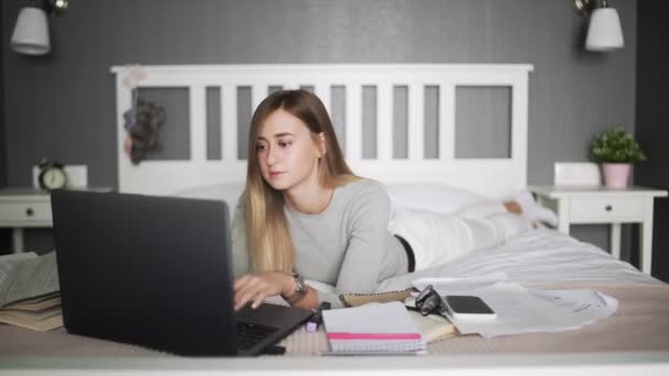 Ung flicka kvinna på sängen, distansutbildning för studenter. Coronavirus. Karantän. Kvinnan tittar på en bärbar dator. Frilansare, distansarbete, arbete i hemmet, nätutbildning — Stockvideo