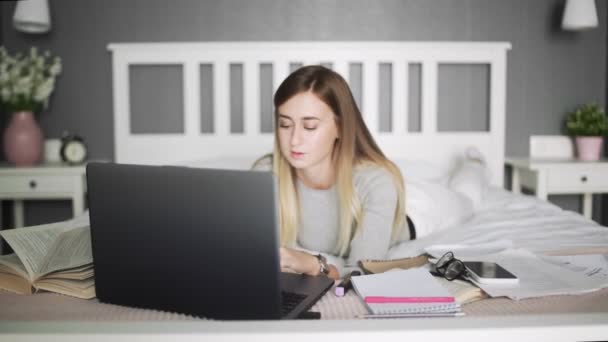 노트를 이용해 침대에 누워 있는 여자. 프리랜서, 집에서 일하기, 사무실 밖에서 일하기. — 비디오