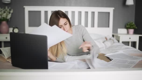 Σοβαρή φοιτήτρια ξαπλώνει στο κρεβάτι και σπουδάζει — Αρχείο Βίντεο