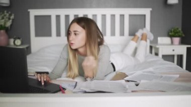 Genç bir kadın evde çalışıyor. Kadın yatağa uzanıyor ve müzik dinliyor.