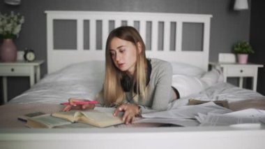 Evde okuyan genç bir kız öğrenci, online eğitim. Genç bayan kitap okuyor.