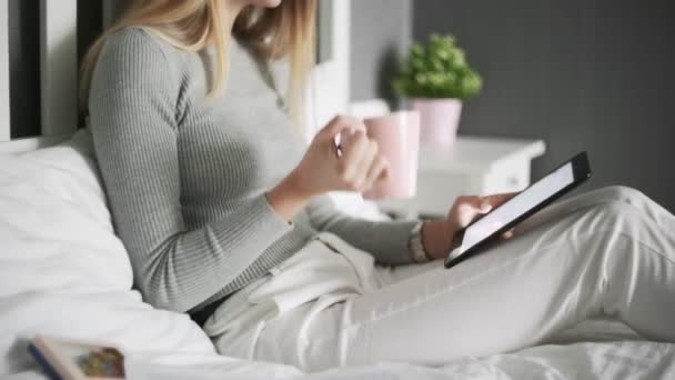 Close up de mulher deitada na cama, bebendo um café e usando tablet — Vídeo de Stock