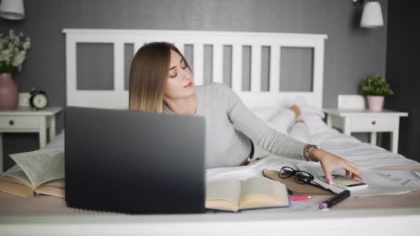 Een jonge vrouw werkt thuis. vrouw ligt op het bed en neemt een selfie op de telefoon — Stockvideo