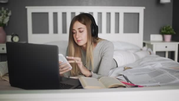 Mujer joven con galsess acostado en la cama y el uso de teléfono inteligente — Vídeos de Stock