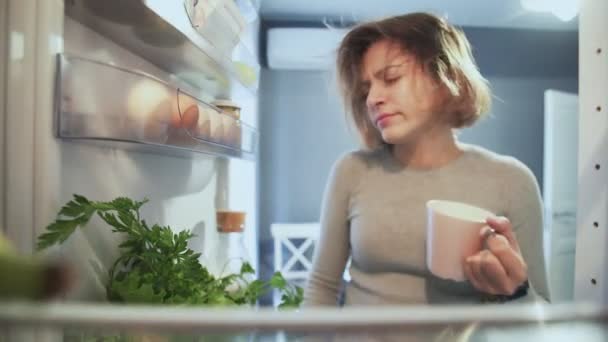 Buzdolabının içinden dışarı bakan kadın, sabahları kapısının önünde çöreklerini yiyor. — Stok video