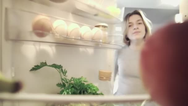 Vista Olhando para fora de dentro da geladeira Como mulher abre a porta e leva uma maçã — Vídeo de Stock