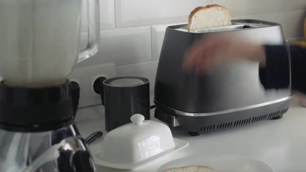 Jovem de pijama preto preparando café da manhã pela manhã. Mulher espalha manteiga no pão torrado — Vídeo de Stock