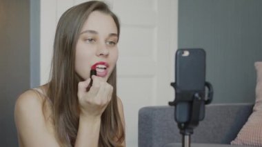 Genç güzel blogcu videosunu kaydederken kızlara makyaj ve güzellik kozmetikleri hakkında ders veriyor. Kadın dudak boyuyor.