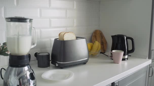 Крупный план молодой женщины в черной пижаме, готовящей завтрак по утрам. Женщина берет легкий жареный хлеб из тостера — стоковое видео