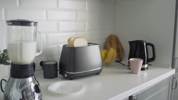 Primer plano de la joven en pijama negro preparando el desayuno por la mañana. Mujer toma un pan tostado ligero de tostadora — Vídeos de Stock