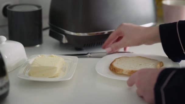 女性はパンのローストスライスに白いバターを広げるためにナイフを使用しています — ストック動画