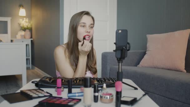 Jovem bela blogueira gravando seu vídeo enquanto tutora meninas sobre maquiagem e beleza cosméticos significa. Mulher pinta lábios — Vídeo de Stock