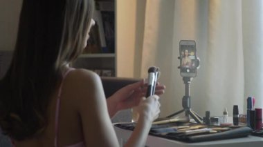 Güzel bir kadının arka görüntüsü akıllı telefonunda fırçayla selfie çeker.