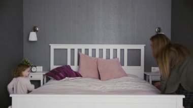Aktif bir anne, bebek bakıcısı ve küçük tatlı bir kız çocuğu. Yatak odasında oynuyorlar. Mutlu bir aile annesi ve çocuk kızı eğleniyorlar.