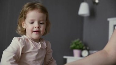 Aktif genç anne bakıcısı ve yatak odasında oynayan sevimli küçük kız çocuğu. Mutlu küçük kız pamuklu çubuklarla oynuyor.