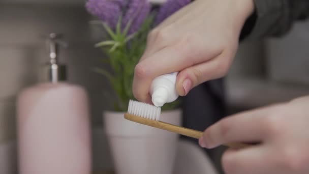 Primer plano de la mujer pone pasta de dientes en el cepillo de dientes — Vídeo de stock