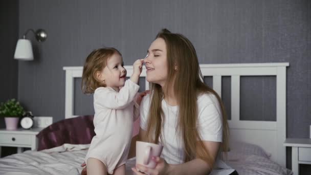 Feliz mami joven jugando con linda hija pequeña adorable niño pequeño. Niña juega con hisopos de algodón — Vídeo de stock