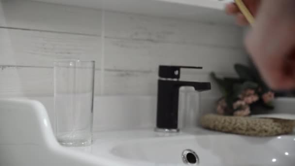 Close-up do homem pega uma escova de dentes de bambu e limpa com água — Vídeo de Stock