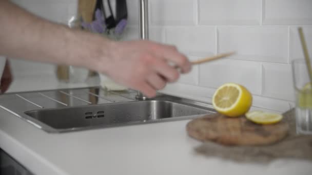 Primer plano de hombre joven lava cuchillo de bambú en la cocina — Vídeos de Stock