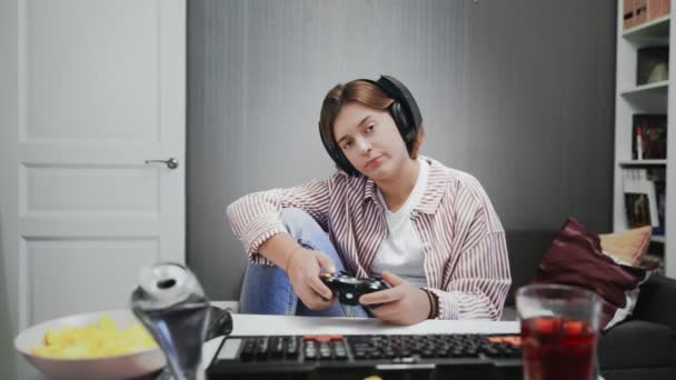 Unalmas fiatal játékos lány játszik videojátékok egy konzol egy vezeték nélküli vezérlő — Stock videók