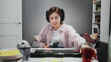 Genç Oyuncu Kız bir konsolda oyun oynuyor ve meyve suyu içiyor.