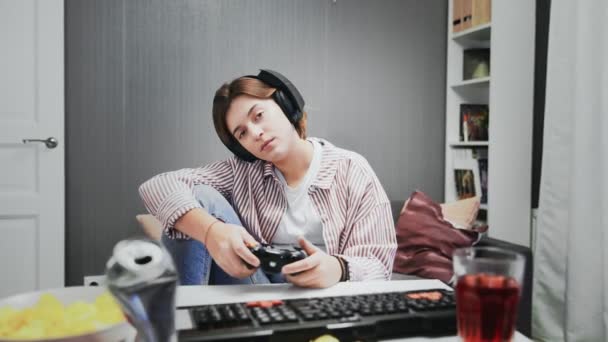 ワイヤレスコントローラーを搭載したコンソールでビデオゲームで遊ぶ若いゲーマーの女の子を退屈 — ストック動画