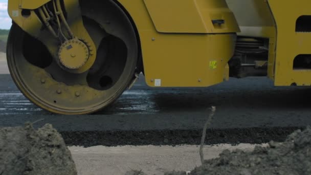 Nahaufnahme des frischen, heißen Asphalts auf der neuen Straße. Straßenbau. Asphaltfertiger während Straßenbau- und Reparaturarbeiten. — Stockvideo