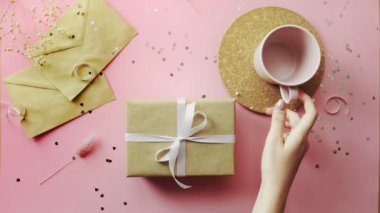 Ahşap pembe masanın en üst görüntüsü. El işi kağıt ve boş bardakta iki posta konseri var.