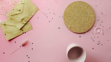 Kadın elleri boş bir bardak ve beyaz kurdeleyle sarılmış bir Noel hediyesi alıyor. Tahta, pembe masa, düz uzanma.