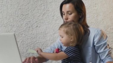 Anne, bebek bebekle evde çalışıyor. Ağlayan çocuk ve stresli kadın. Evde kal.