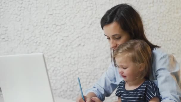 Joven madre está dando jugo a su bebé de biberón y trabajando en el cuaderno — Vídeos de Stock