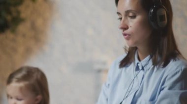 Küçük bebeği resim yaparken kulaklıklı bir kadının evde çalışması..