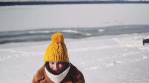 Jonge vrouw in bontjas gooit sneeuw op in de winter — Stockvideo