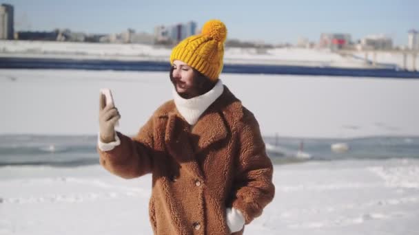 Jonge vrouw met beugels op tanden in bont jas neemt een selfie outdoor — Stockvideo