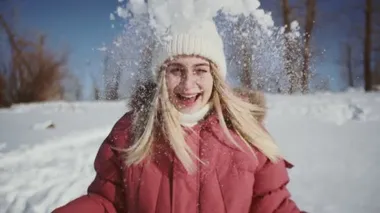 Beyaz örgü şapkalı ve kırmızı ceketli güzel kadın kar kusuyor.