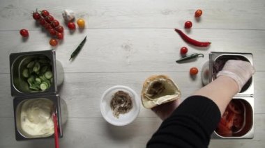Ekmeğin içinde shawarma yapan eldivenli profesyonel şefin elleri. Eldivenli şef shawarma 'ya soğan turşusu koyar.