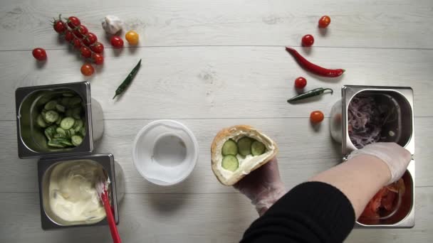 Visão superior de mãos do chef profissional em luvas que fazem shawarma no pão. Chef em luvas coloca tomates em shawarma — Vídeo de Stock