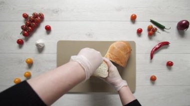 Plastik kesim tahtasında taze ekmek kesmenin en üst görüntüsü.