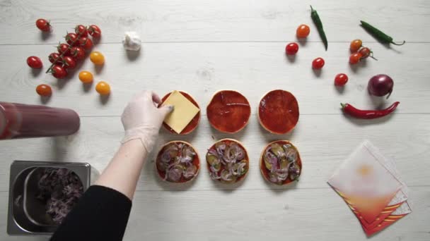 Vue de dessus du chef professionnel cuisine un délicieux hamburgers au restaurant de restauration rapide. Femme chef dans des gants met du fromage sur trois hamburgers — Video