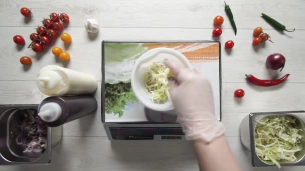 Chefe em luvas pesa repolho em tigela de plástico em balanças de cozinha — Vídeo de Stock