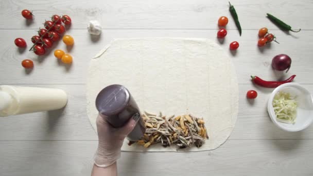 Horní pohled na ruce šéfkuchaře v bílých rukavicích dává BBQ souse na doner kebab shawarma v pita nebo lavash. Vaření shawarma s kuřecím masem, hranolky, sýrem a zeleninou